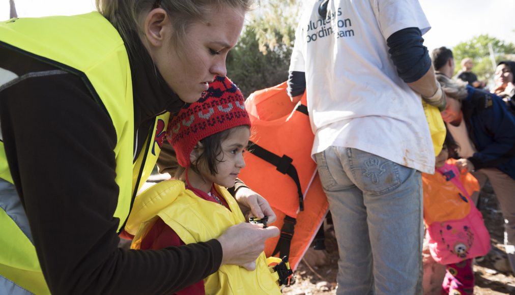 Octobre 2015, Lesbos: une bénévole norvégienne aide une petite fille à retirer son gilet de sauvetage après qu&#039;elle a parcouru 10 kilomètres en haute mer sur un canot de fortune. / IStock